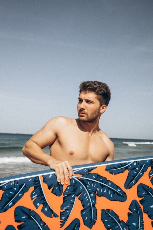 A Shirtless Man Holding a Surfboard