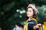 在泰国，一名年轻女子头戴花冠、身穿毕业礼服参加户外活动