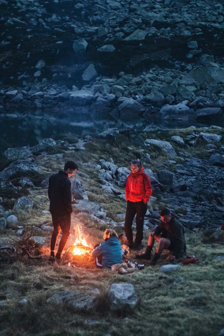 People Around A Bonfire On A Rocky Green Grass