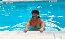 夏日阳光明媚，一位穿着泳装的女子在泳池里开心地笑着玩耍