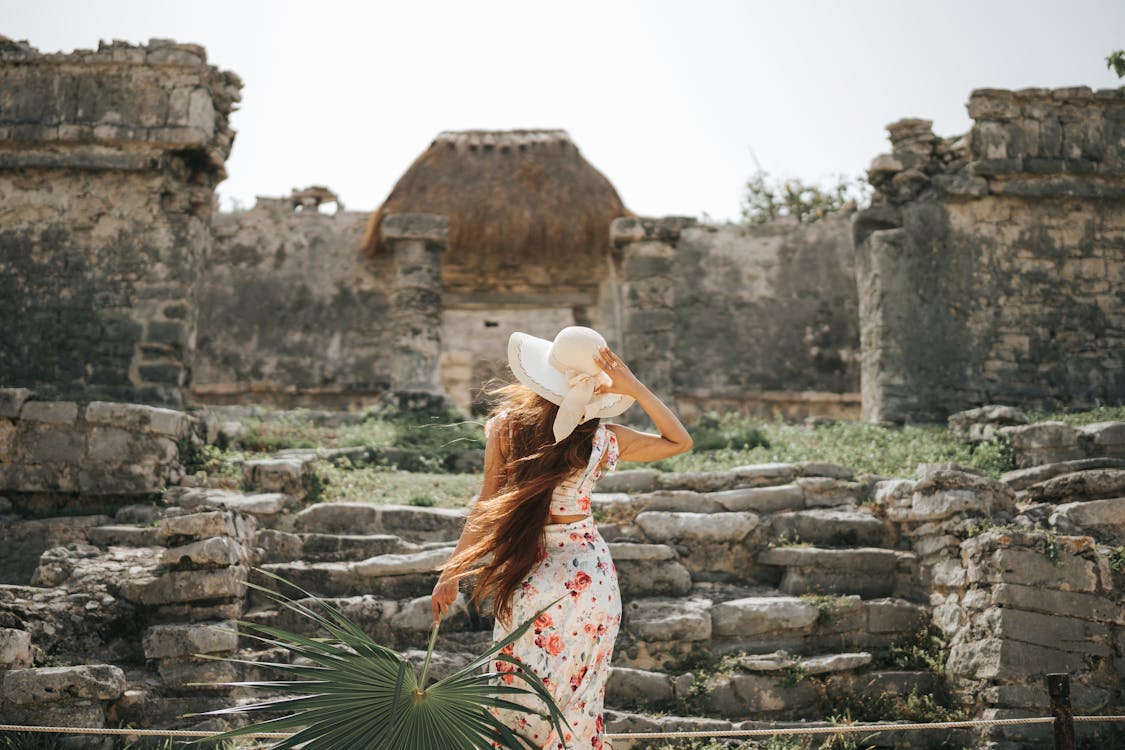 Free Back View o Woman in a Summer Outfit Looking at House of the Halach Uinic at Mayan Ruins in Tulum, Mexico Stock Photo