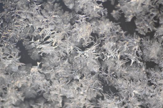 Close-up view of frost crystals on a surface, showcasing intricate icy textures.