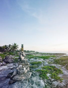 日出时分的热带海滩宁静宜人，石像、棕榈树和葱郁的绿植点缀其间