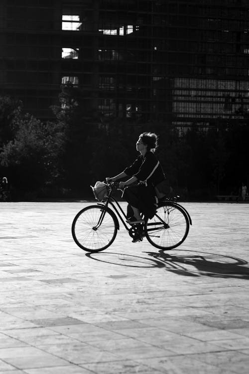 Grayscale Photo of a Woman Riding a Bike