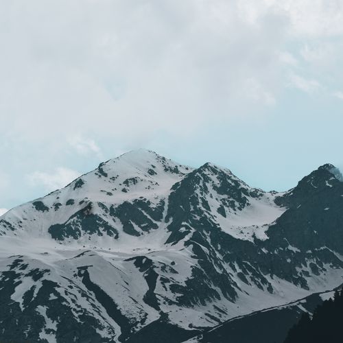 Free Breathtaking snow-covered mountain range beneath a cloudy sky, showcasing the beauty of nature. Stock Photo