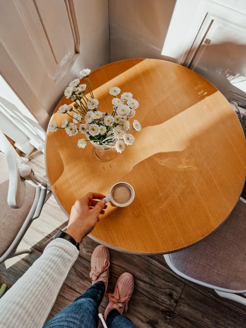 Top View of a Person Holding a Cup of Coffee on a Tabletop