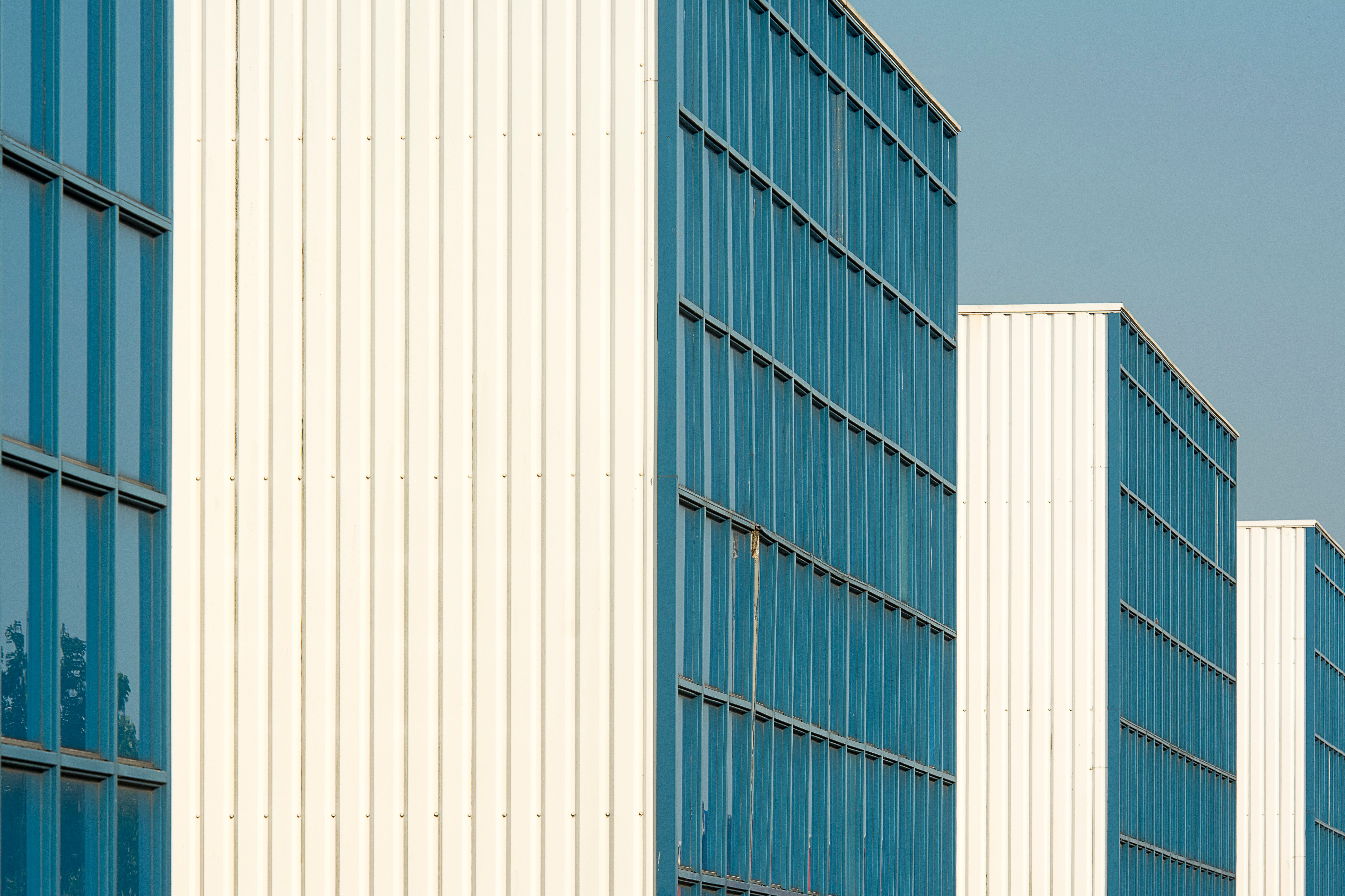 Close-up of modern white and blue building facades with reflective windows under a clear sky.