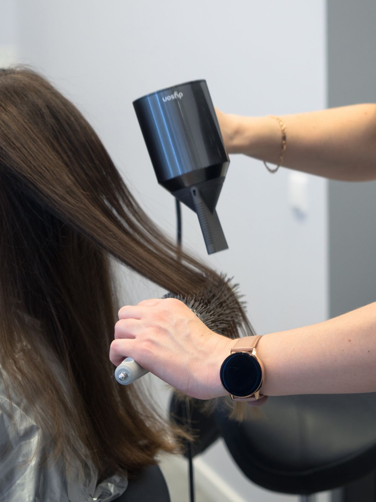 Hairdresser styling hair with a professional hair dryer and brush