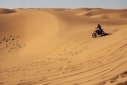 Free A thrilling ride across vast sandy desert dunes, showcasing motocross adventure in a barren landscape. Stock Photo