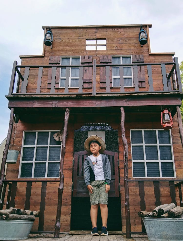 Boy Standing On A Porch Of A House 