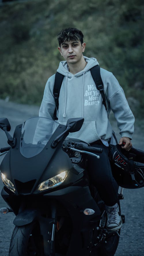 Man in a Gray Hoodie Sitting on a Black Motorcycle