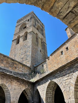 A stunning low angle view of a gothic castle tower with clear blue skies, showcasing intricate stonework.