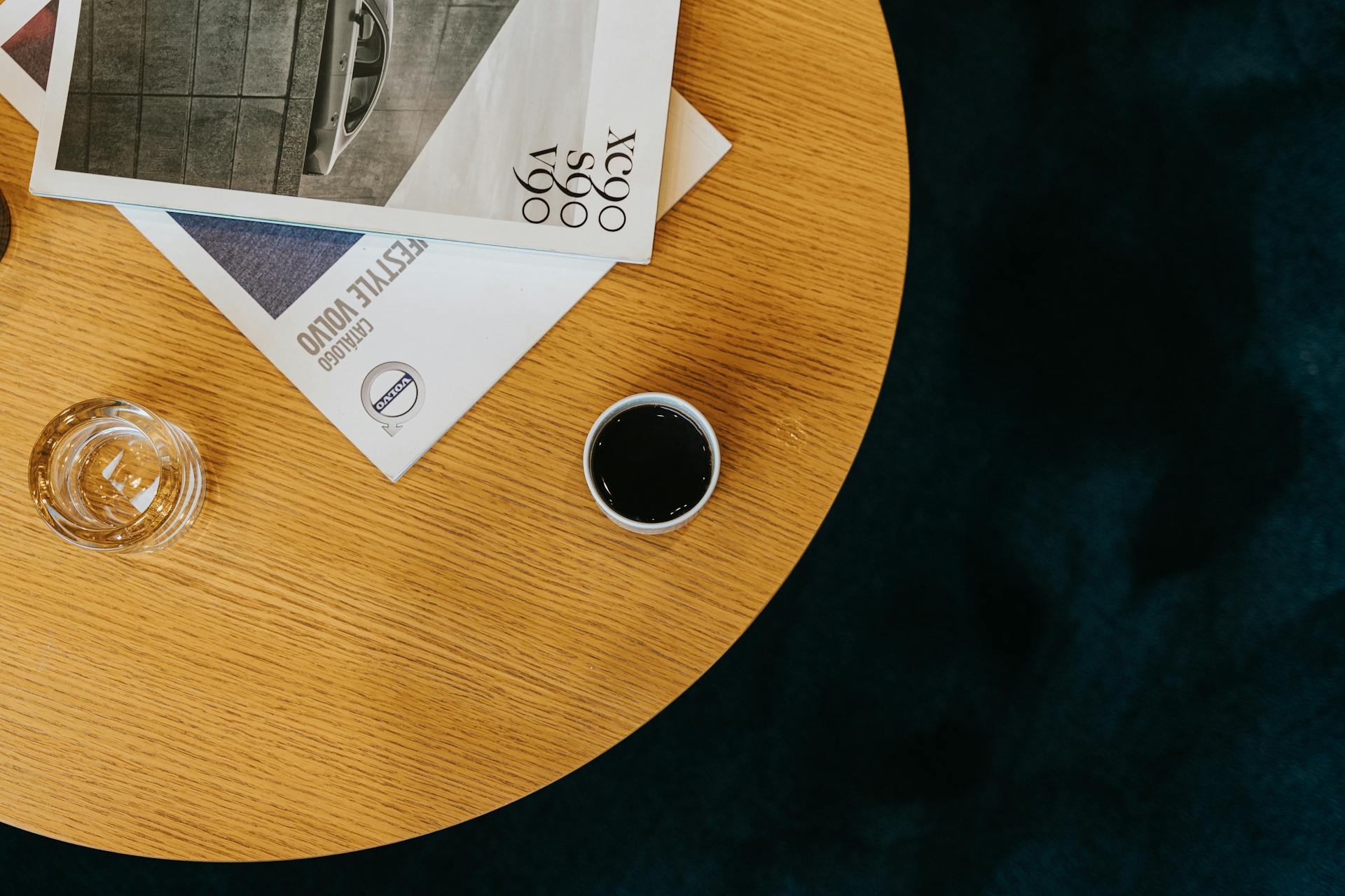 Stylish composition of coffee, glass, and magazines on a wooden table in Curitiba, Brazil.