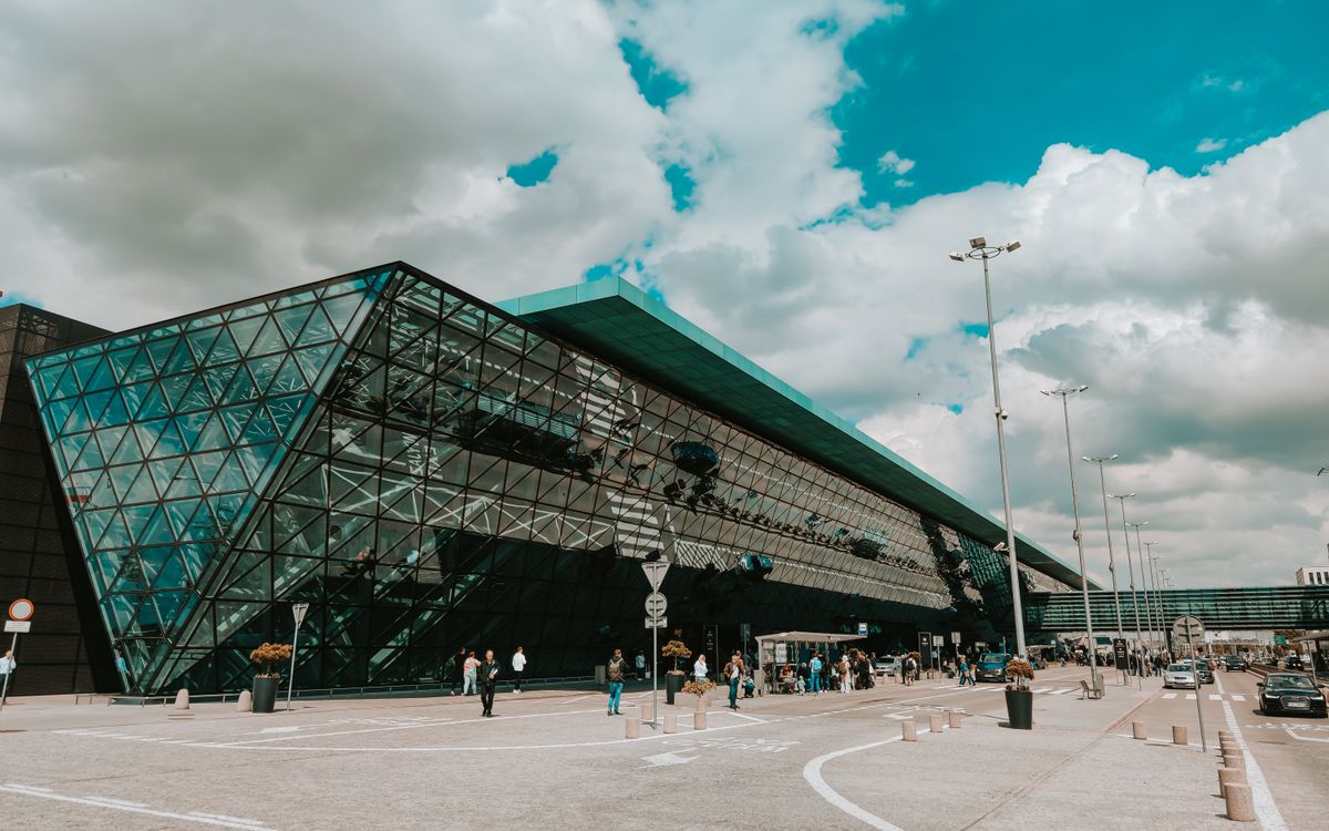 Contemporary airport terminal featuring striking glass facade under a cloudy sky.