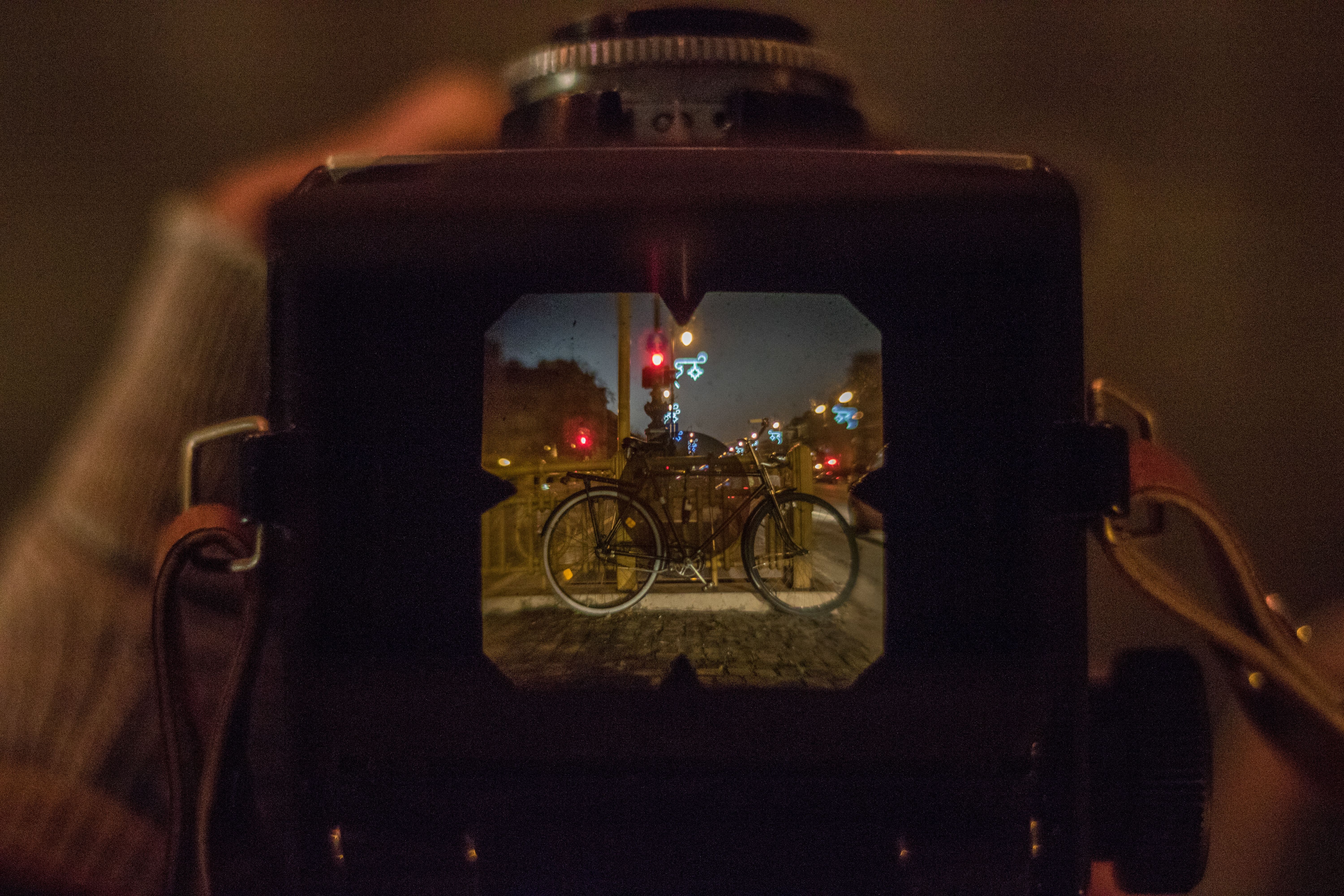 Bicycle viewed through a camera viewfinder in an urban night setting in Budapest.