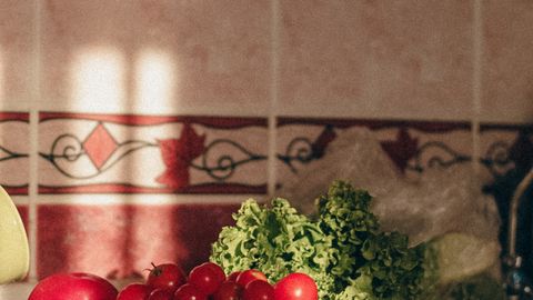 Close-up of fresh vegetables on a kitchen counter with natural light highlighting tomatoes and greens.