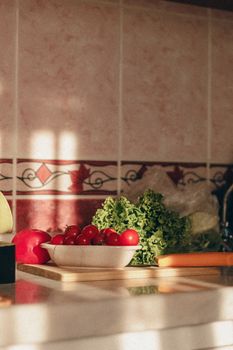 Close-up of fresh vegetables on a kitchen counter with natural light highlighting tomatoes and greens.
