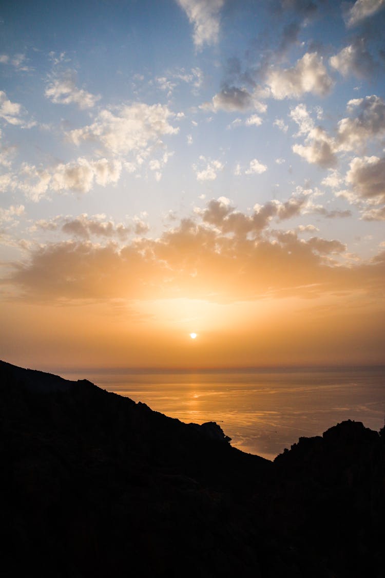 Silhouette Of Mountain Near Sea During Sunset