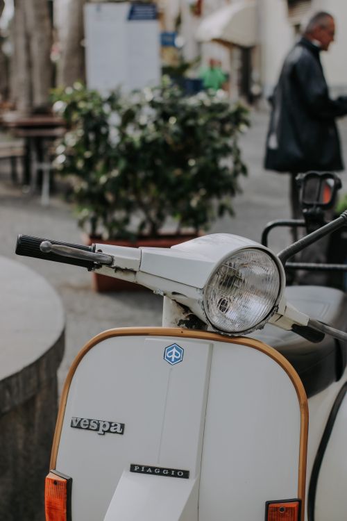 Free A classic white Vespa scooter, stylishly parked on a city street, evokes a sense of nostalgia. Stock Photo
