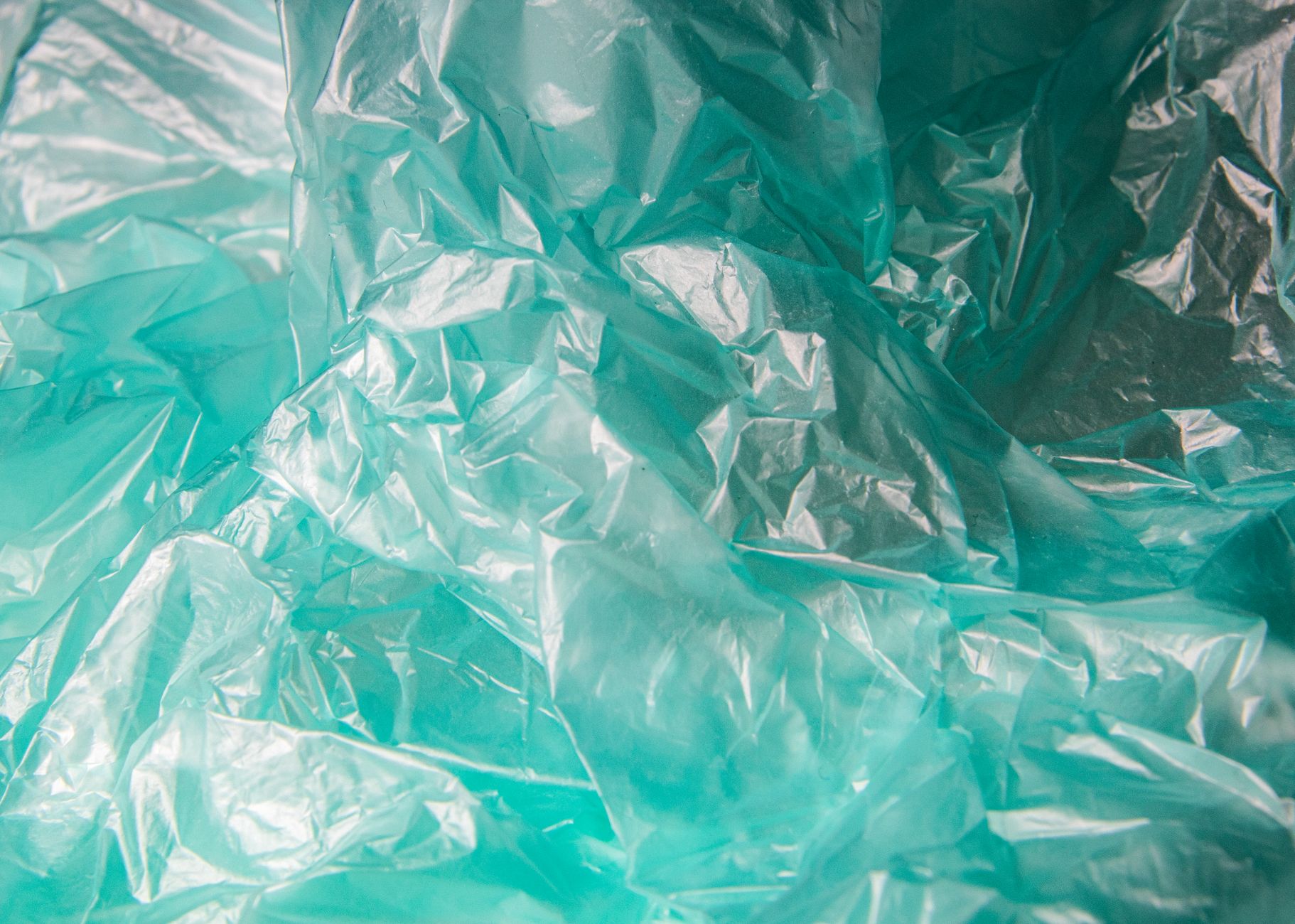 Detailed close-up of crumpled blue plastic texture showcasing patterns and transparency.