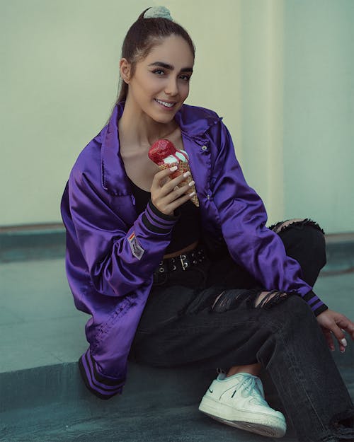 A Smiling Woman in Purple Jacket Holding an Ice Cream Cone