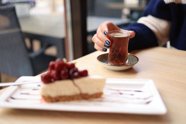 Elegant tea time setup with cheesecake and glass of tea on a cozy table setting.
