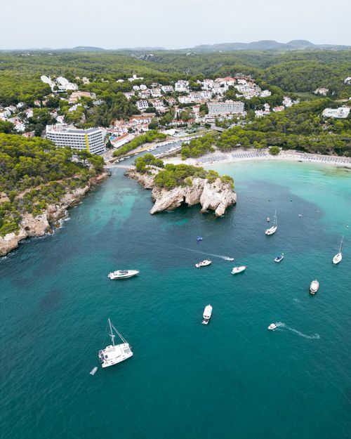 Free Aerial shot of the scenic Cala Galdana cove in Menorca, Spain with boats and hotels. Stock Photo