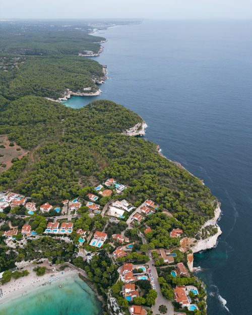 Free Stunning aerial view of Cala Galdana, Menorca, showcasing lush greenery and clear seas. Stock Photo