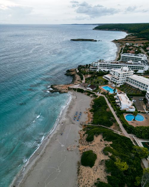 Free Breathtaking aerial view of Sant Tomas beach and resort in Spain, showcasing serene coastline and vibrant blue sea. Stock Photo