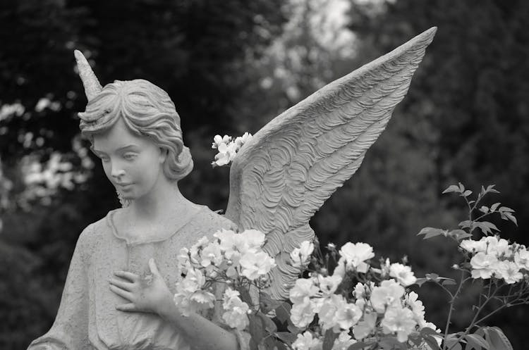 Angel Statue With Wings Beside Flowers