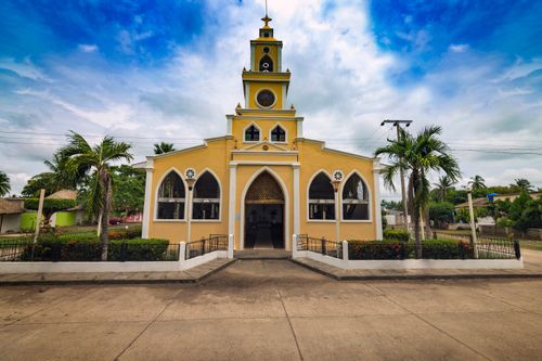 Free A vibrant yellow church facade with palm trees in Córdoba, Nariño, Colombia. Stock Photo