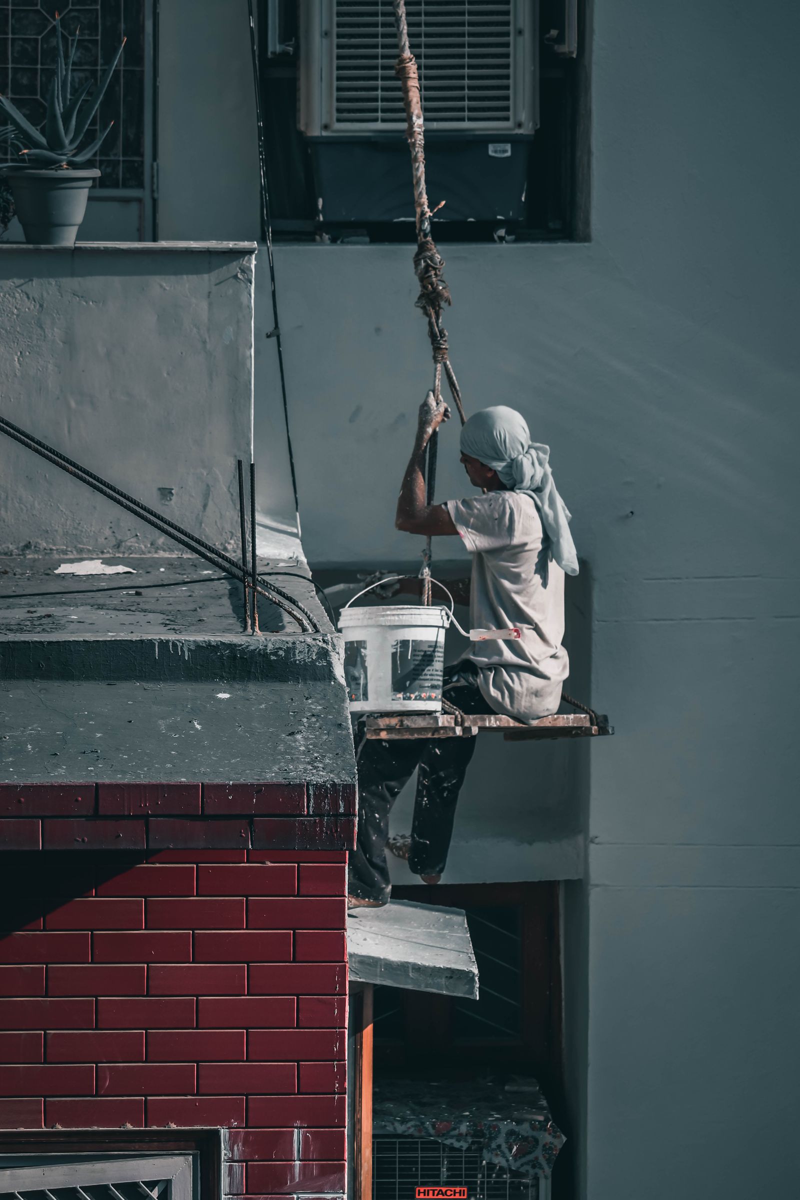 Indian painter on a scaffold repainting a premium building exterior in Mumbai Indian painter on a scaffold repainting a premium building exterior in Mumbai