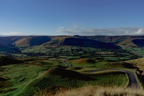 Free Breathtaking landscape of rolling hills and winding road under a clear blue sky. Stock Photo