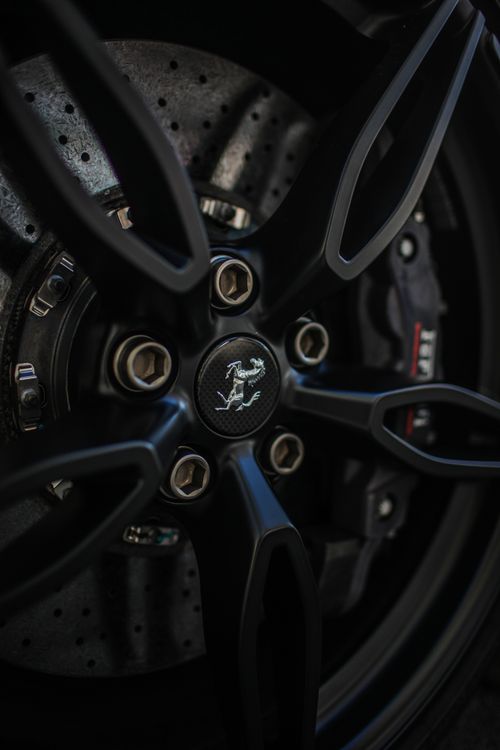 Free Detailed view of a sports car wheel featuring intricate rim design and recognizable logo. Stock Photo