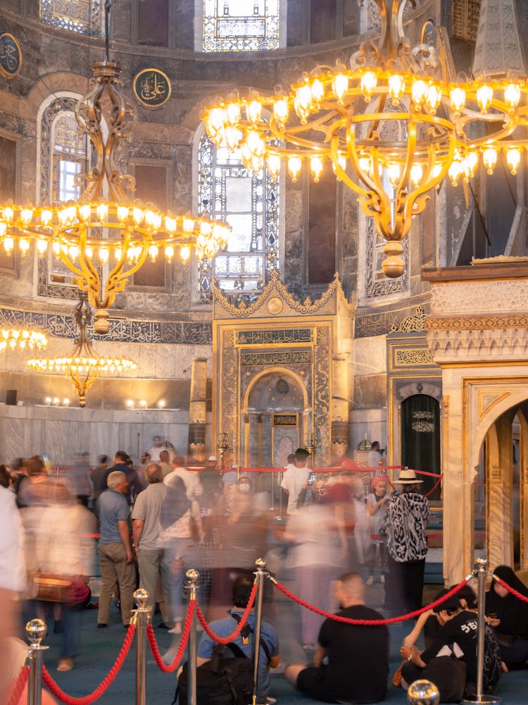 People Walking Inside The Building With Chandeliers