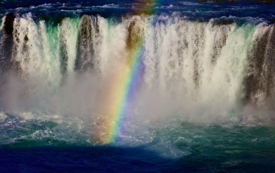 A breathtaking view of a powerful waterfall with a vivid rainbow, creating a magical scene.