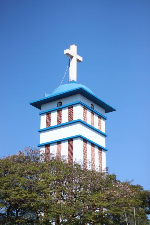 Free A striking church tower with a white cross under a clear blue sky, showcasing cultural architecture. Stock Photo