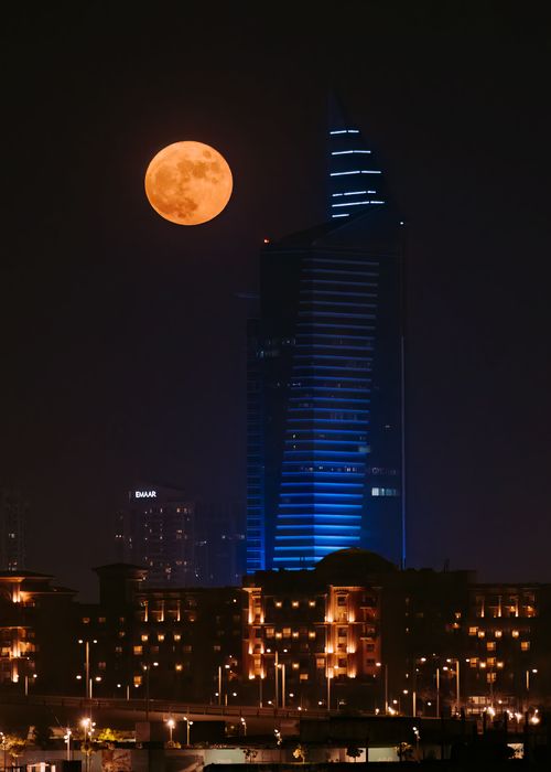 Free Stunning view of Dubai's skyline at night, featuring a full moon and illuminated skyscrapers. Stock Photo