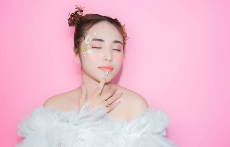 Portrait Of Woman With Flowers Drawn On Face On Pink Back