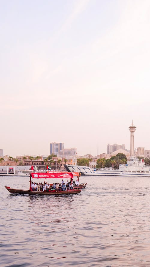 Free People on Red Boat Near Gray Pavement With View of City Stock Photo