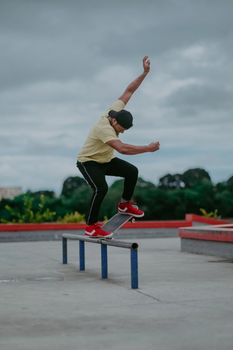 A skateboarder executes a move on a rail in an outdoor skate park. Dynamic and energetic action shot.