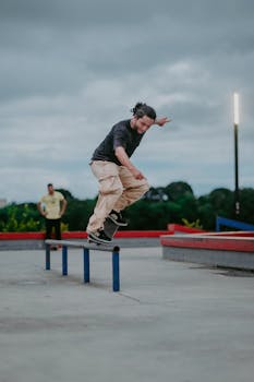 A skateboarder performing a trick on a rail in an outdoor urban skate park.