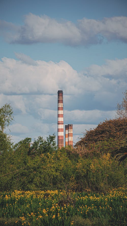 Red and White Smokestacks of a Power Plant Under White Clouds