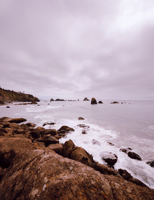 Free Ocean Waves Crashing on Brown Rocks at the Seashore  Stock Photo