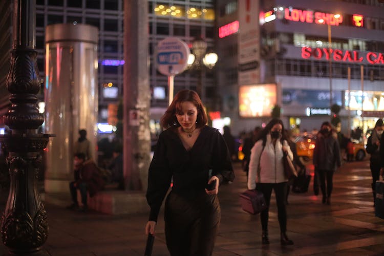 A Woman Walking In The Street At Night