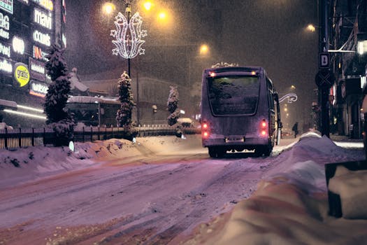 A city street at night covered in snow with an illuminated bus, capturing the essence of winter urban life.