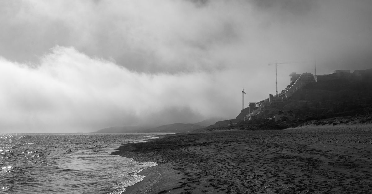 mysterious foggy coastal town at dusk with eerie ocean waves
