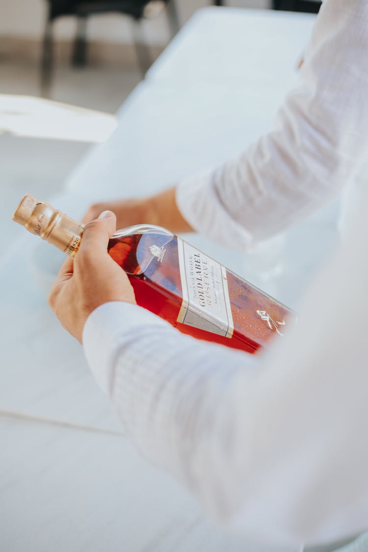 Photo Of A Person Holding A Bottle Of Whiskey