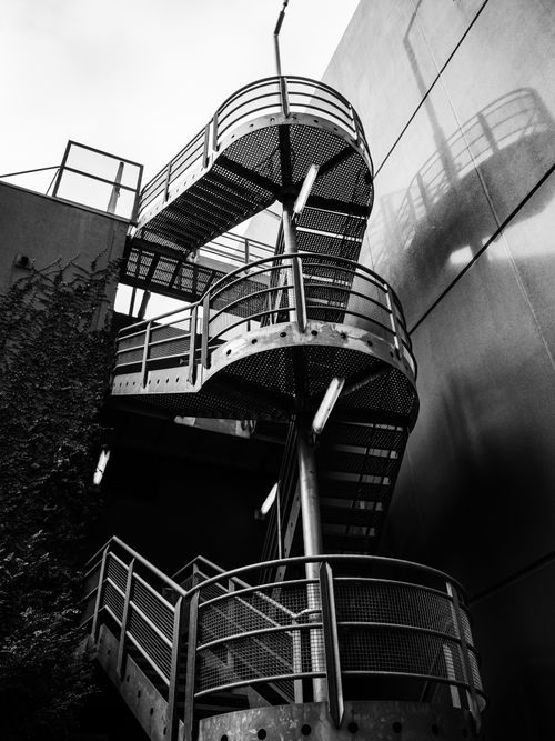 Free Artistic black and white photo of a spiral staircase with dramatic shadows. Stock Photo