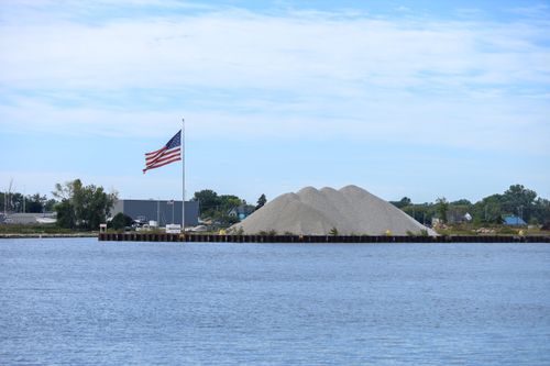 Free A beautiful harbor scene with an American flag and gravel piles by the water. Stock Photo